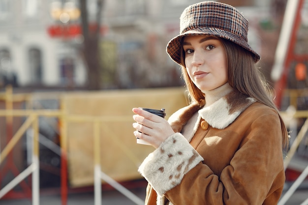 Menina andando em uma cidade de primavera e tomando café