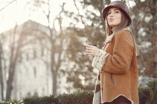 Menina andando em uma cidade de primavera e tomando café