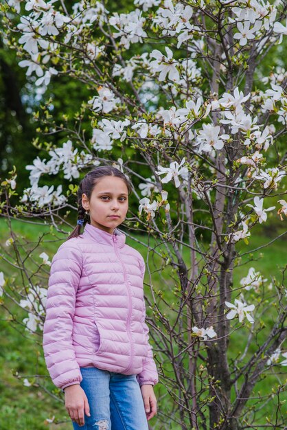 Menina ao lado de uma árvore em flor