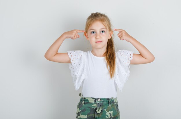 Menina apontando o dedo para as têmporas em uma camiseta branca