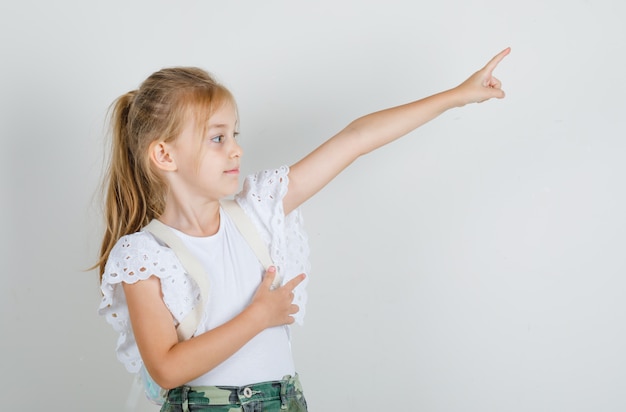 Menina apontando o dedo para longe em uma camiseta branca