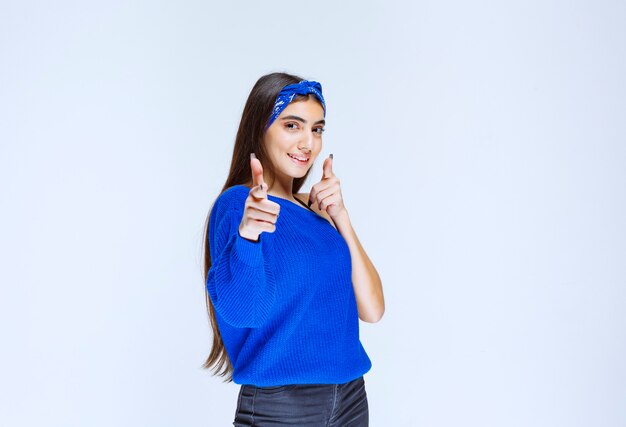 Menina apontando para alguém à frente e convidando-o ou perguntando algo.