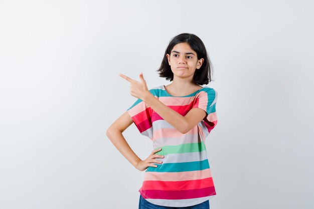 Menina apontando para o canto superior esquerdo da camiseta e olhando pensativa. vista frontal.