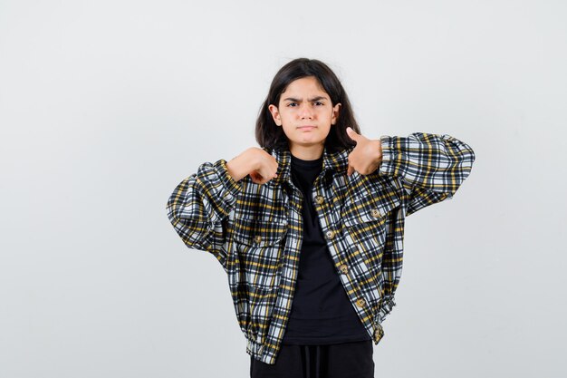 Menina apontando para si mesma em t-shirt, jaqueta e olhando confiante, vista frontal.