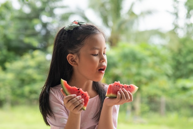 Menina asiática comendo melancia