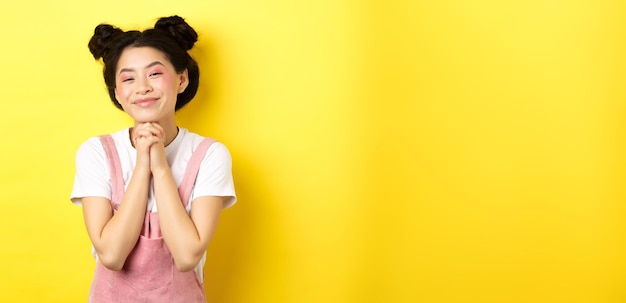 Foto grátis menina asiática estilosa com maquiagem brilhante diz obrigado sorrindo grata por estar feliz em fundo amarelo