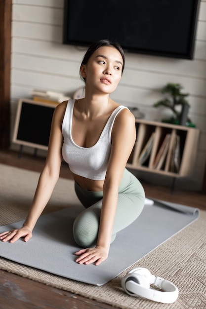 Menina asiática fazendo ioga, alongamento e treino em casa na sala de estar, usando roupas esportivas