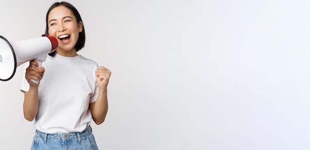 Menina asiática gritando no megafone jovem ativista protestando usando alto-falante fazendo anúncio