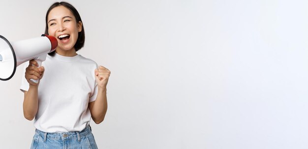 Menina asiática gritando no megafone jovem ativista protestando usando alto-falante fazendo anúncio