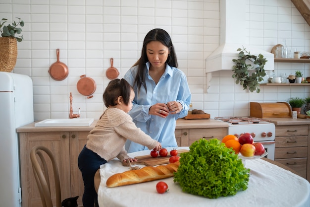 Foto grátis menina asiática passando em casa na cozinha com a mãe