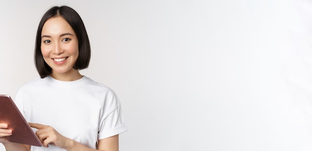 Menina asiática usando tablet digital trabalhando com compras de gadgets on-line sobre fundo branco