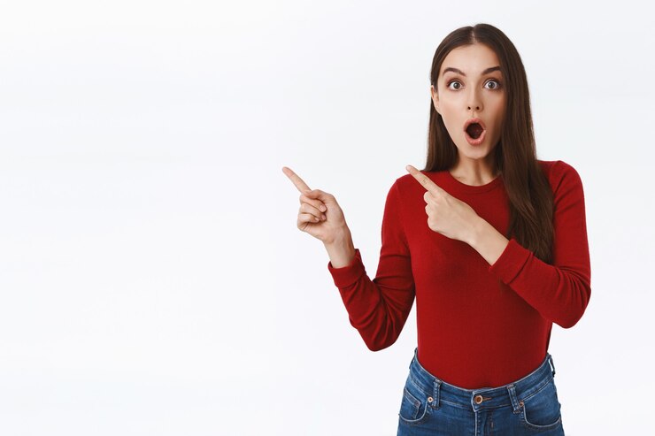Foto grátis menina atônita parece muito surpresa ao apontar o canto superior esquerdo para uma oferta maravilhosa e impressionante, lábios dobrados dizendo uau, olhar para a câmera fascinada, sem palavras e com um fundo branco impressionado