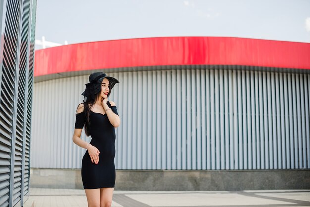 Menina atraente de vestido preto de pé fora