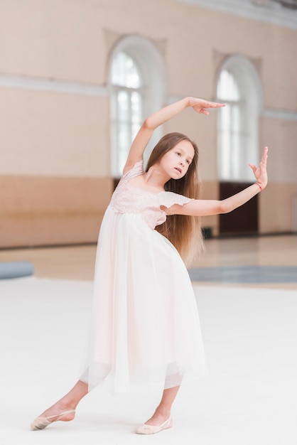 Menina bailarina no vestido rosa posando no estúdio de dança