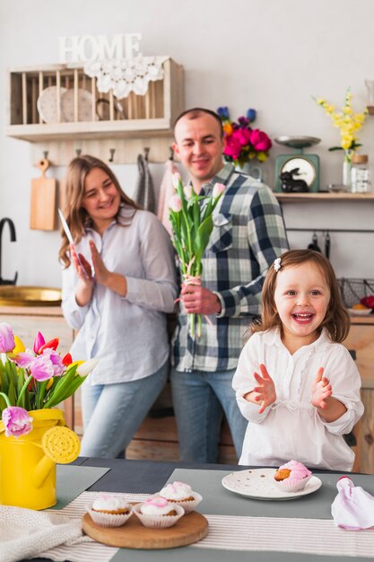 Menina batendo palmas perto de pais com flores