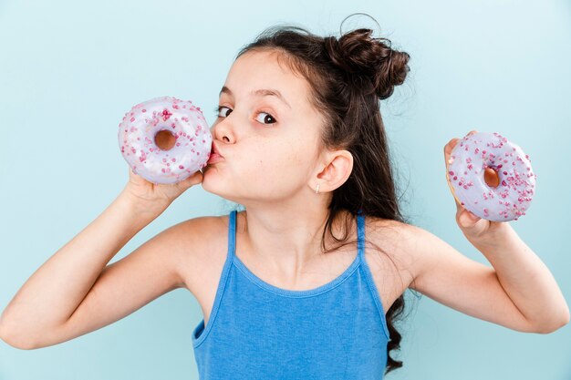 Menina beijando rosquinha deliciosa