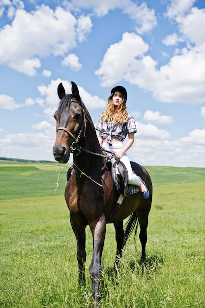 Menina bonita andando a cavalo em um campo em dia ensolarado