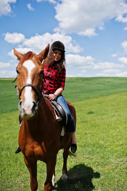 Menina bonita andando a cavalo em um campo em dia ensolarado