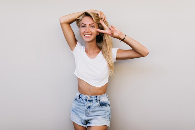 Menina bonita bronzeada posando com um sorriso alegre em estúdio. Mulher jovem europeia bonita com dança desportiva