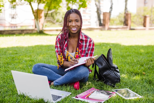 Foto grátis menina bonita com estudos posando no parque