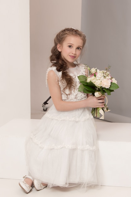 Menina bonita com flores vestidas em vestidos de noiva