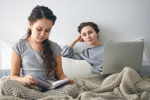 Menina bonita com longos cabelos escuros lendo livro no quarto