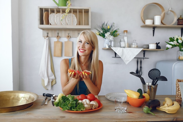 Menina bonita e alegre em uma cozinha com legumes