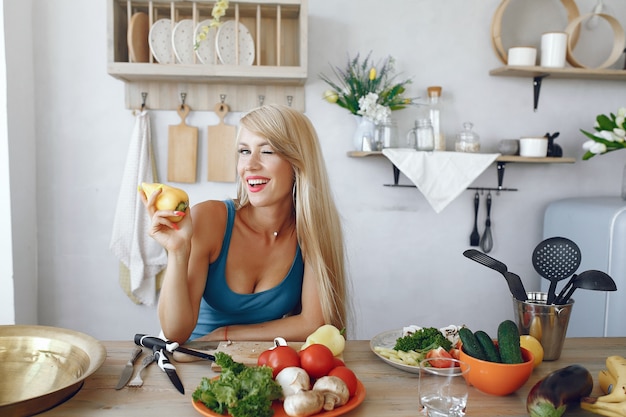 Menina bonita e alegre em uma cozinha com legumes