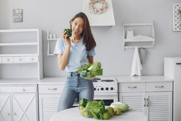 Menina bonita e alegre em uma cozinha com legumes