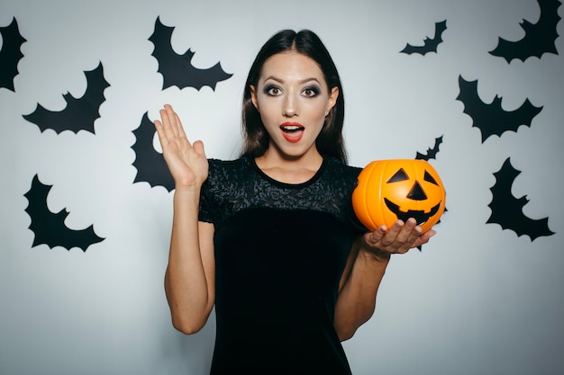 Menina bonita e espantada com abóbora de Halloween