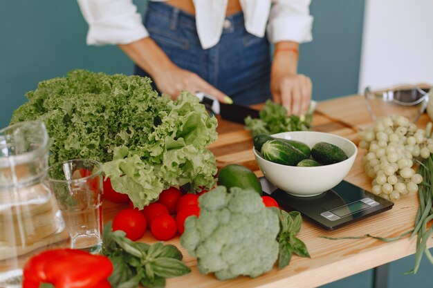 Menina bonita e esportiva em uma cozinha com legumes