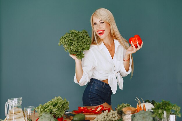 Menina bonita e esportiva em uma cozinha com legumes