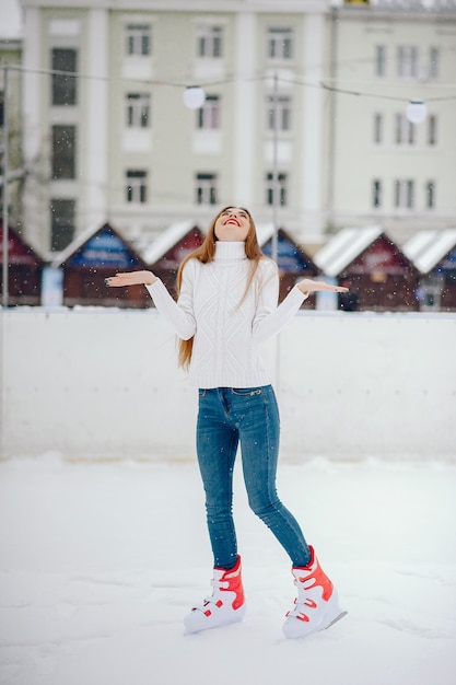 Menina bonita e linda com um suéter branco em uma cidade de inverno