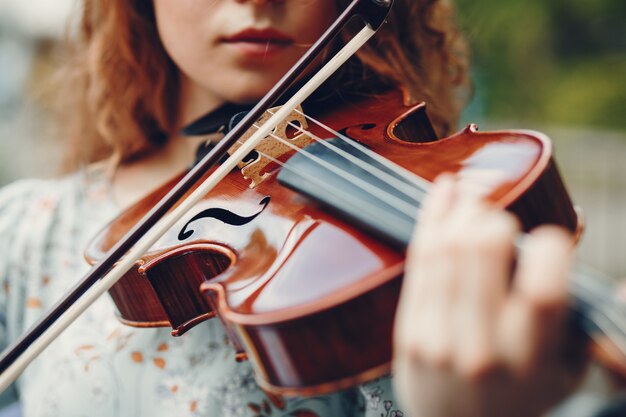 Menina bonita em um parque de verão com um violino