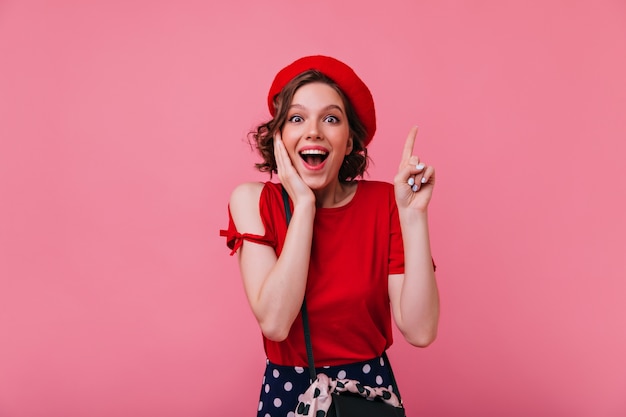 Foto grátis menina bonita espantada com tatuagem que expressa emoções positivas. refinada senhora francesa em boina e t-shirt vermelha.