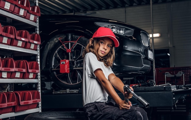 Menina bonita está posando para o fotógrafo enquanto está sentado no serviço de auto escuro segurando a broca pneumática.