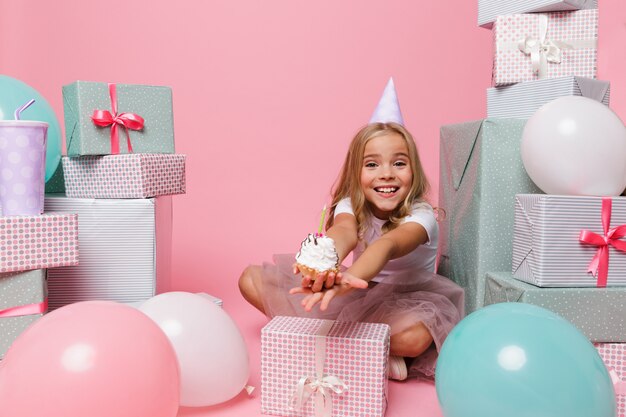 Menina bonita feliz em um chapéu de aniversário comemorando