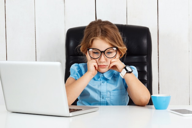 Menina bonita jovem cansada, sentado no local de trabalho no escritório.