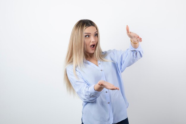 Menina bonita jovem em pé e surpresa em branco.