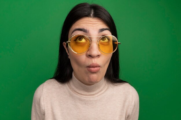 Menina bonita morena caucasiana impressionada com óculos de sol olha para o verde