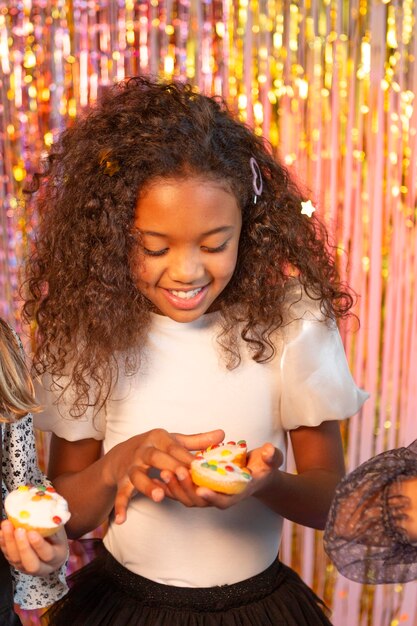 Menina bonita na festa festiva segurando bolinho