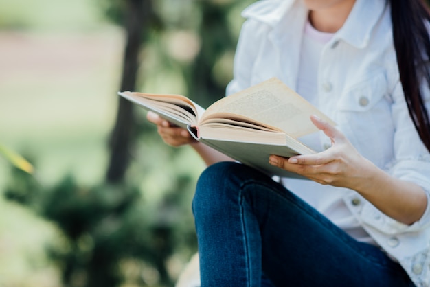 Menina bonita na floresta de outono, lendo um livro