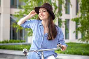 Foto grátis menina bonita no chapéu andando de bicicleta na rua