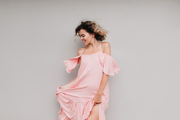 Menina bonita no vestido rosa dançando com expressão de rosto feliz. retrato de modelo feminino alegre que expressa emoções positivas verdadeiras.