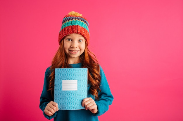 Menina bonita nova que mostra o livro azul da cópia e o sorriso isolado