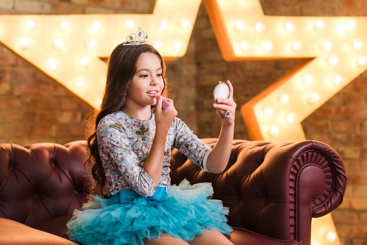 Foto grátis menina bonita que aplica o batom que senta-se no sofá contra a estrela de incandescência