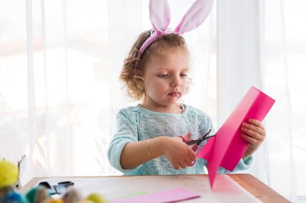 Menina bonita que corta decorações de Páscoa