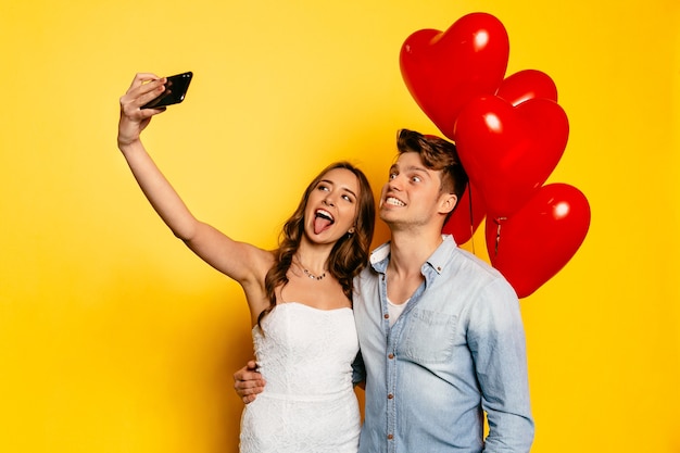 Foto grátis menina bonita que mostra uma língua que está com o noivo que mostra os dentes que tomam o selfie