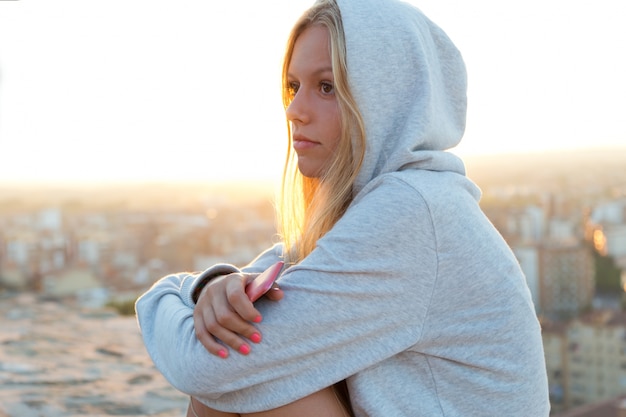 Foto grátis menina bonita que senta-se no telhado e que escuta a música.