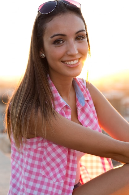 Foto grátis menina bonita que senta-se no telhado no por do sol.